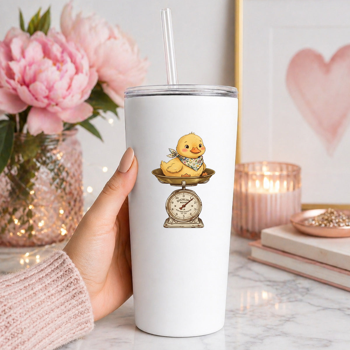 Duckling On Vintage Farm Scale UV DTF sticker applied to a white straw tumbler beside pink peonies