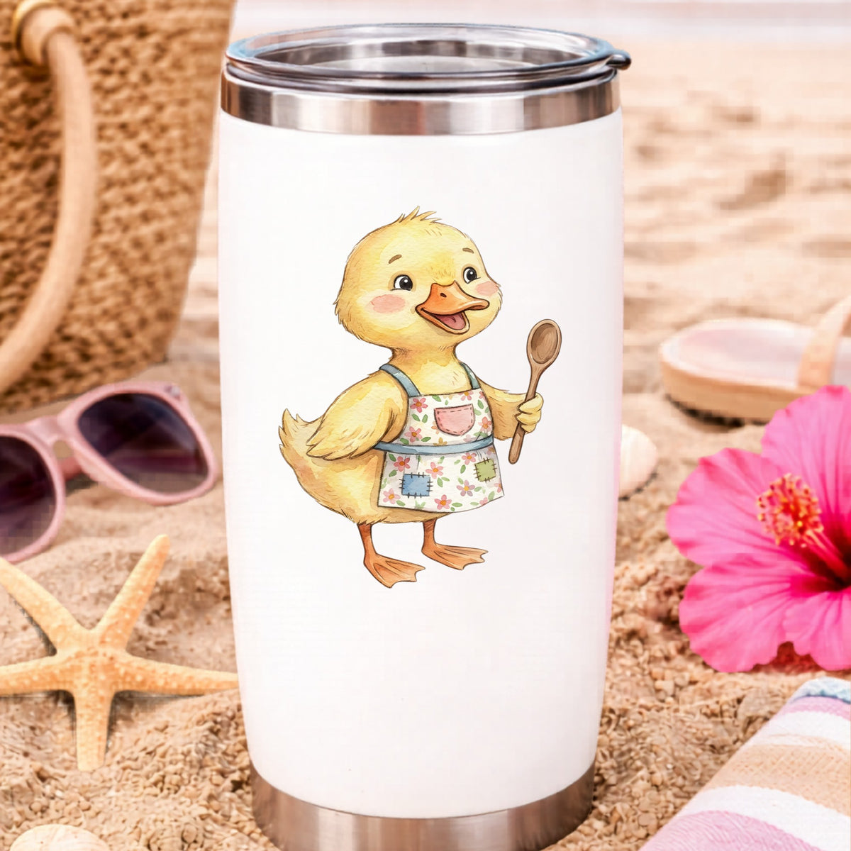 Duckling In Apron With Wooden Spoon UV DTF sticker applied to a white travel tumbler on beach sand