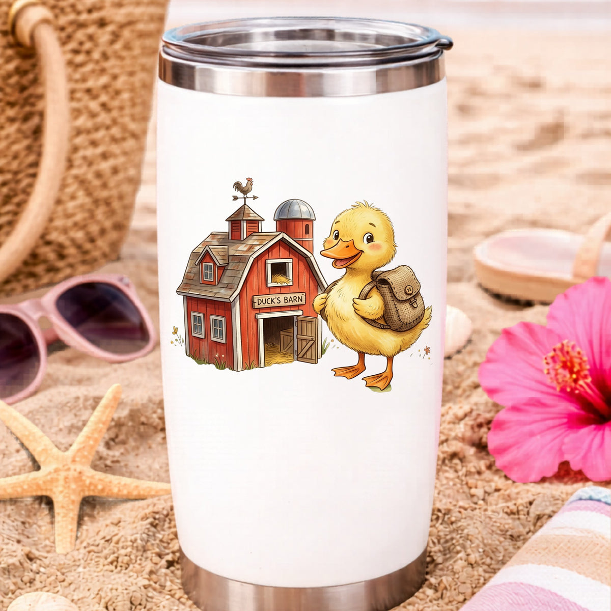 Duckling With Backpack And Red Barn UV DTF sticker applied to a white travel tumbler on beach sand