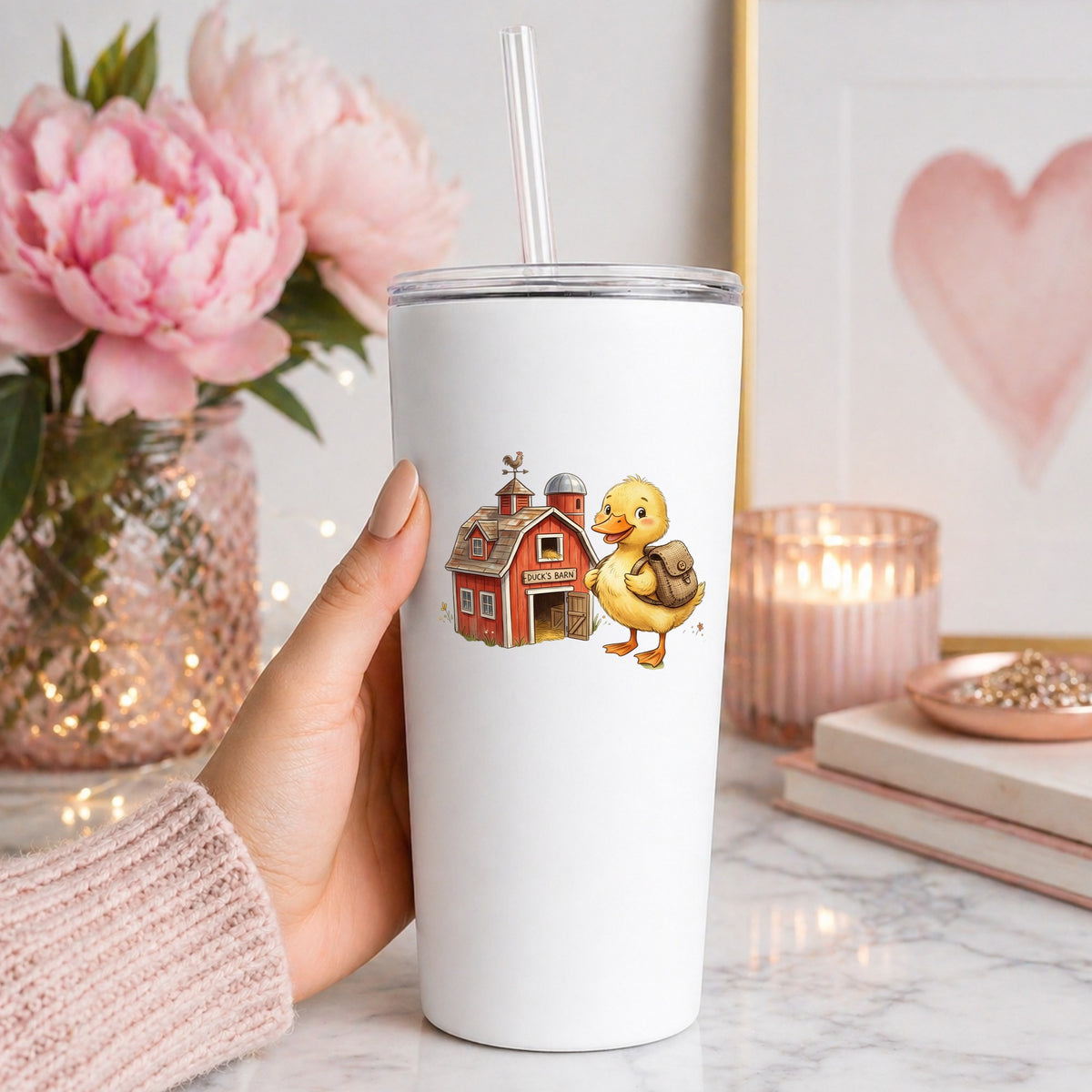 Duckling With Backpack And Red Barn UV DTF sticker applied to a white straw tumbler beside pink peonies