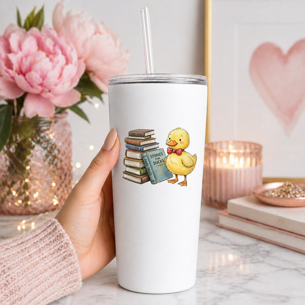 Duckling With Stack Of Storybooks UV DTF sticker applied to a white straw tumbler beside pink peonies