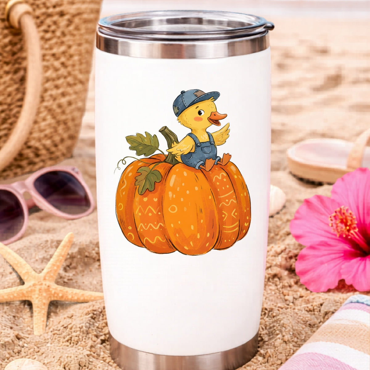 Duckling In Overalls On Pumpkin UV DTF sticker applied to a white travel tumbler on beach sand