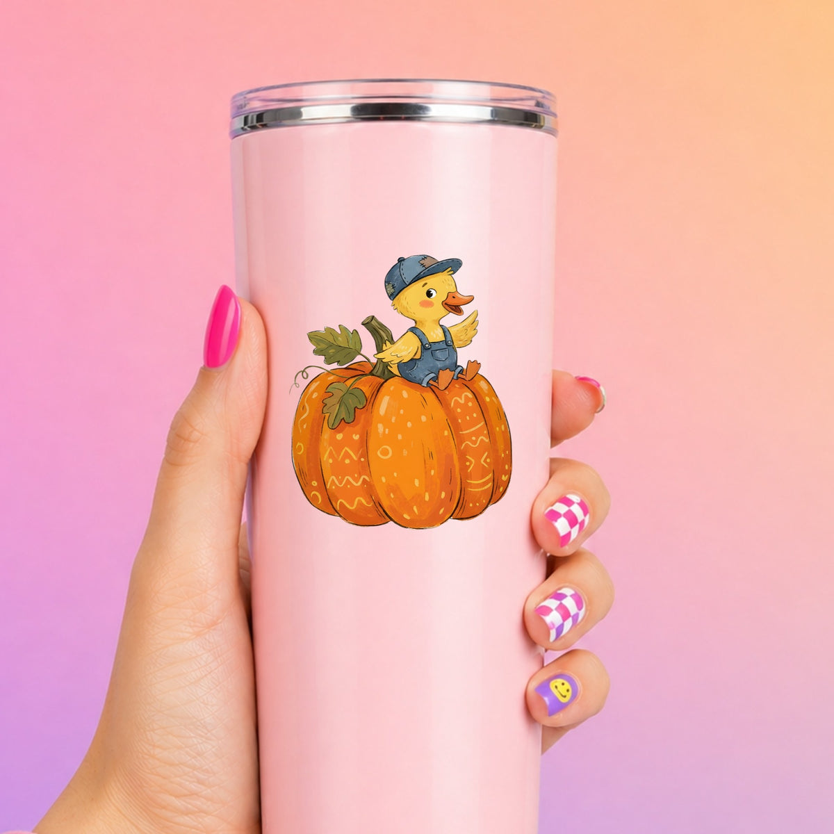 Duckling In Overalls On Pumpkin UV DTF sticker applied to a tall pink tumbler on a pink and orange background