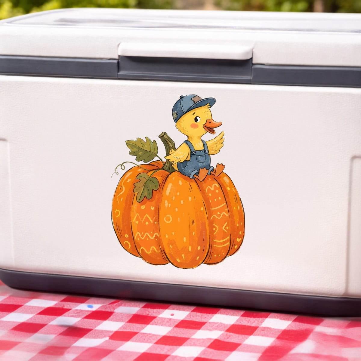 Duckling In Overalls On Pumpkin UV DTF sticker applied to a white cooler on a red gingham cloth