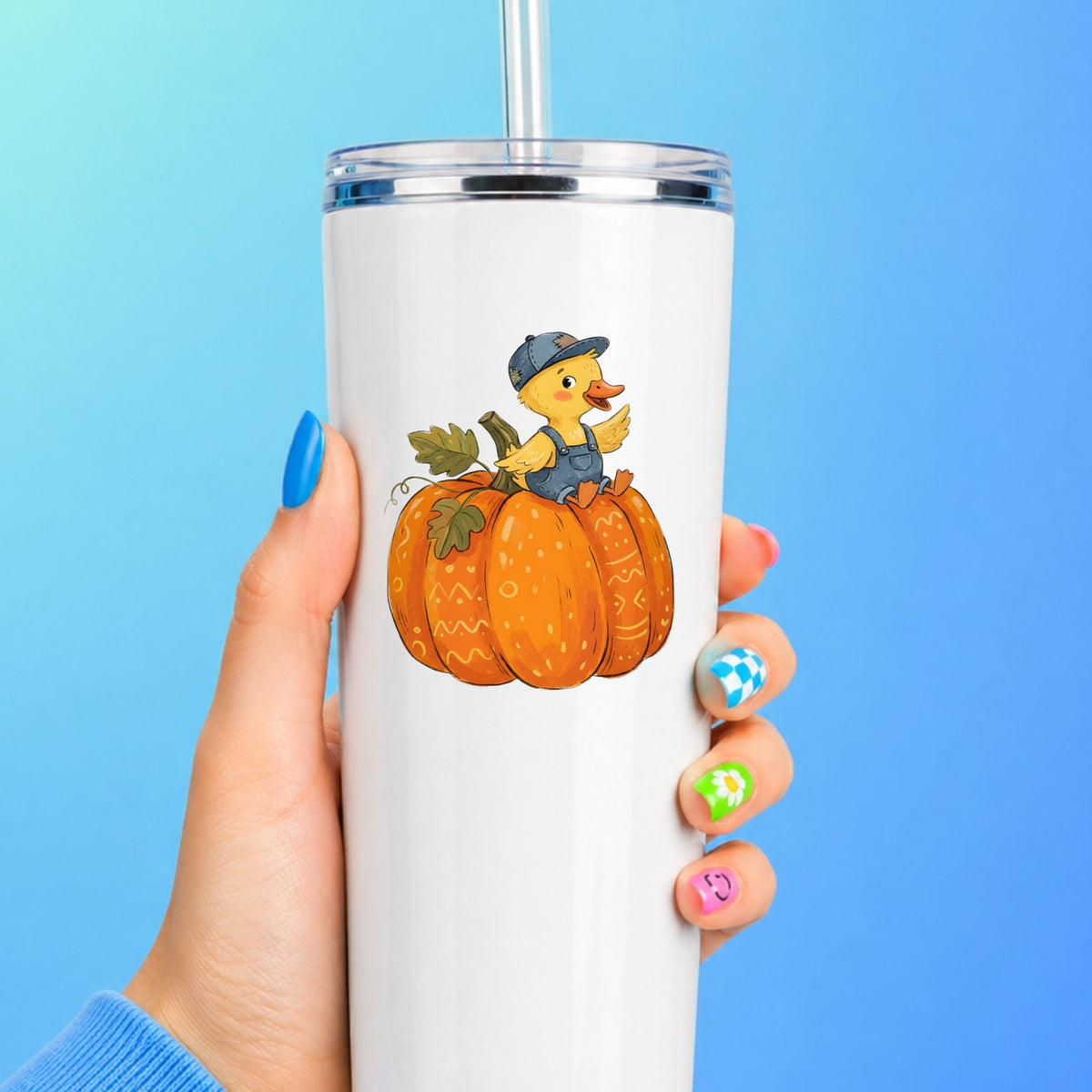 Duckling In Overalls On Pumpkin UV DTF sticker applied to a white straw tumbler on a blue background