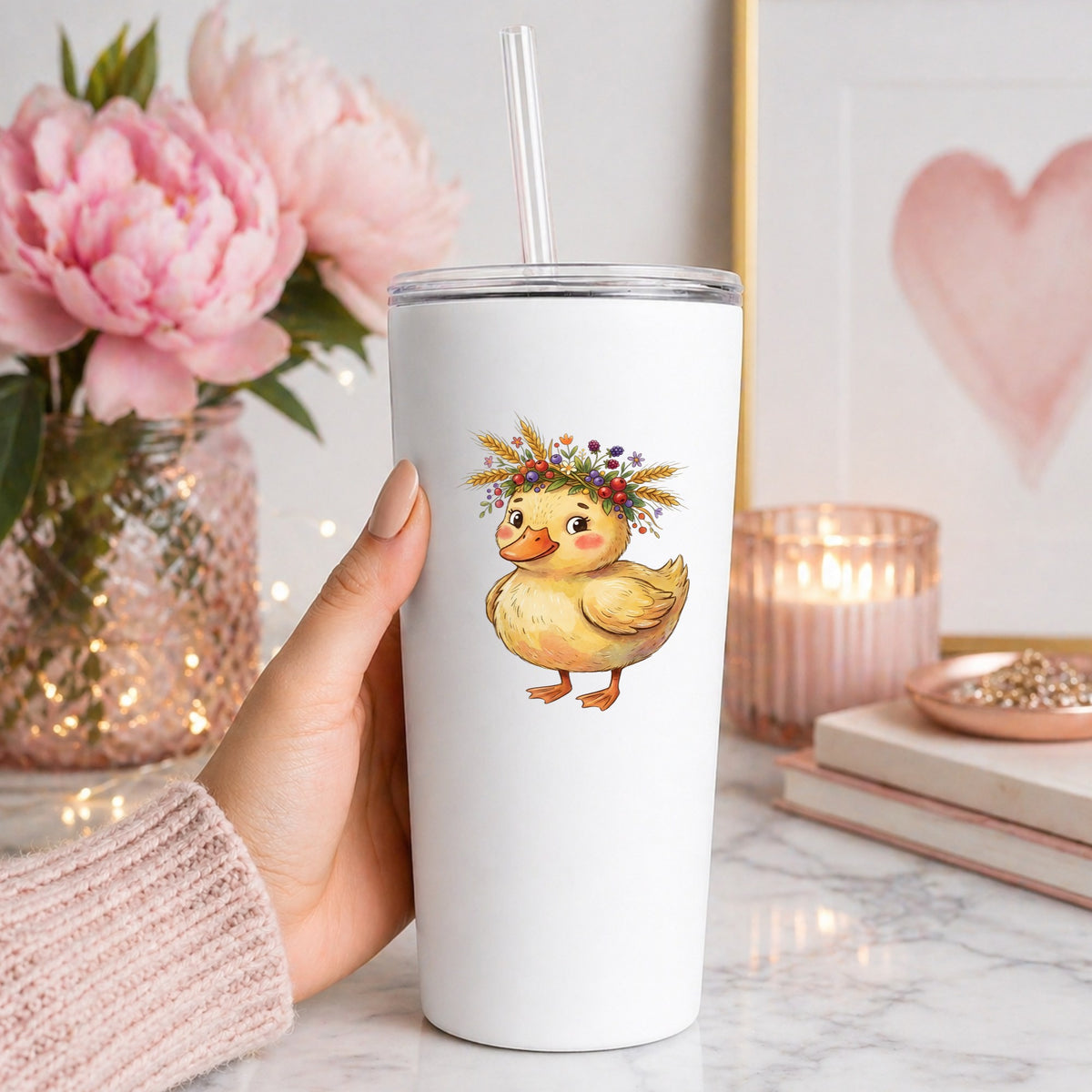 Duckling With Wheat And Berry Crown UV DTF sticker applied to a white straw tumbler beside pink peonies