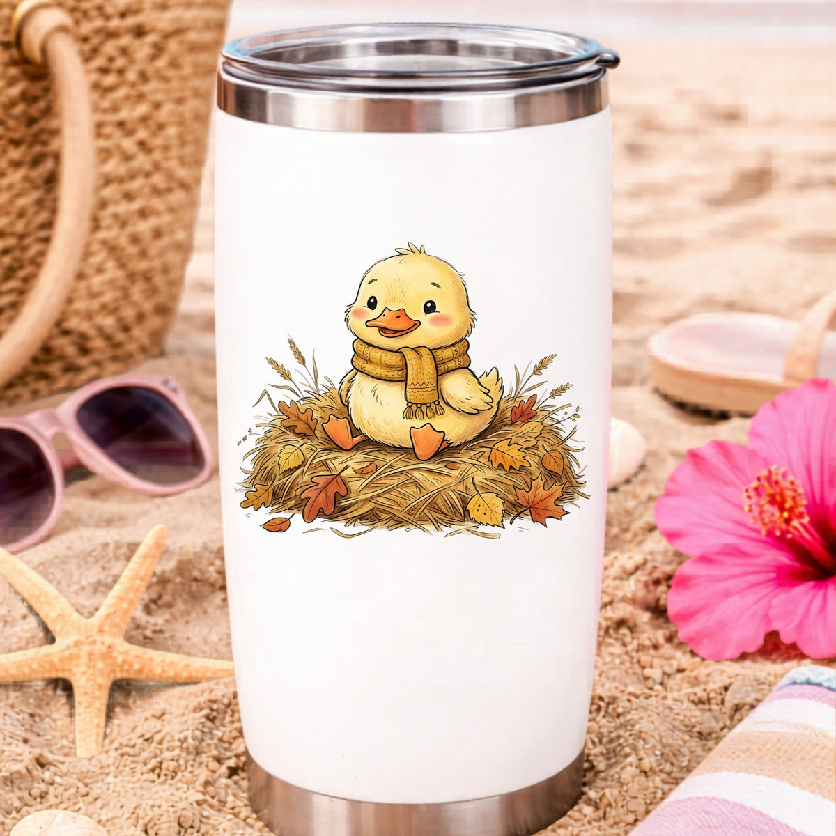 Duckling In Scarf On Hay With Autumn Leaves UV DTF sticker applied to a white travel tumbler on beach sand
