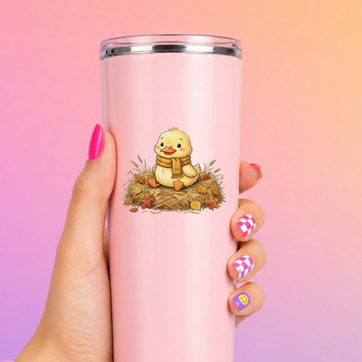 Duckling In Scarf On Hay With Autumn Leaves UV DTF sticker applied to a tall pink tumbler on a pink and orange background
