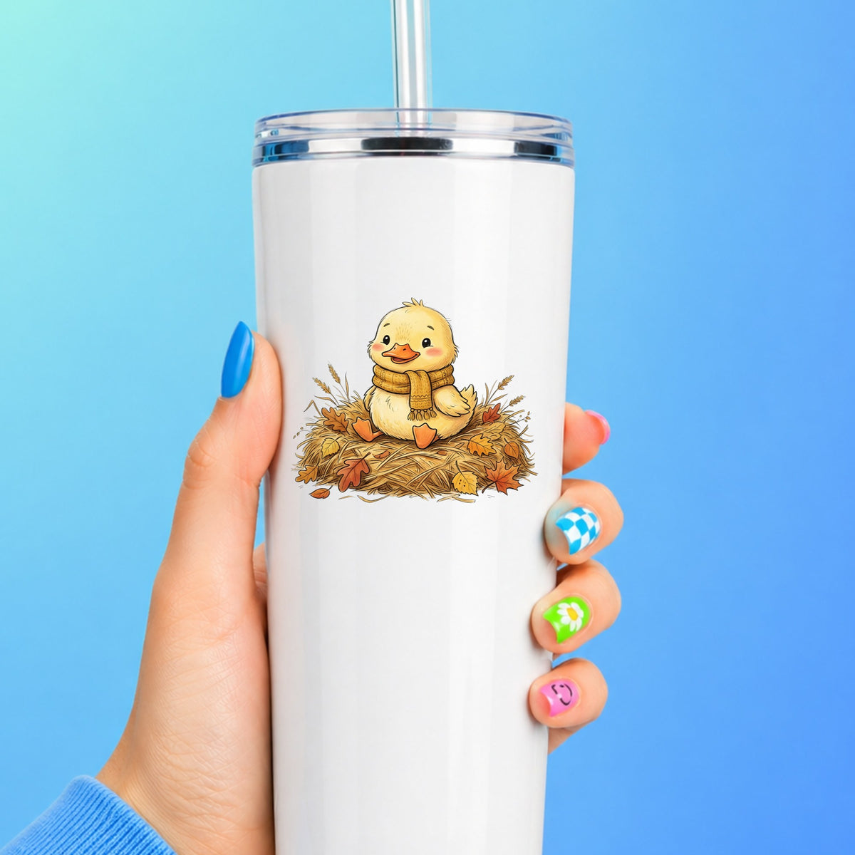 Duckling In Scarf On Hay With Autumn Leaves UV DTF sticker applied to a white straw tumbler on a blue background