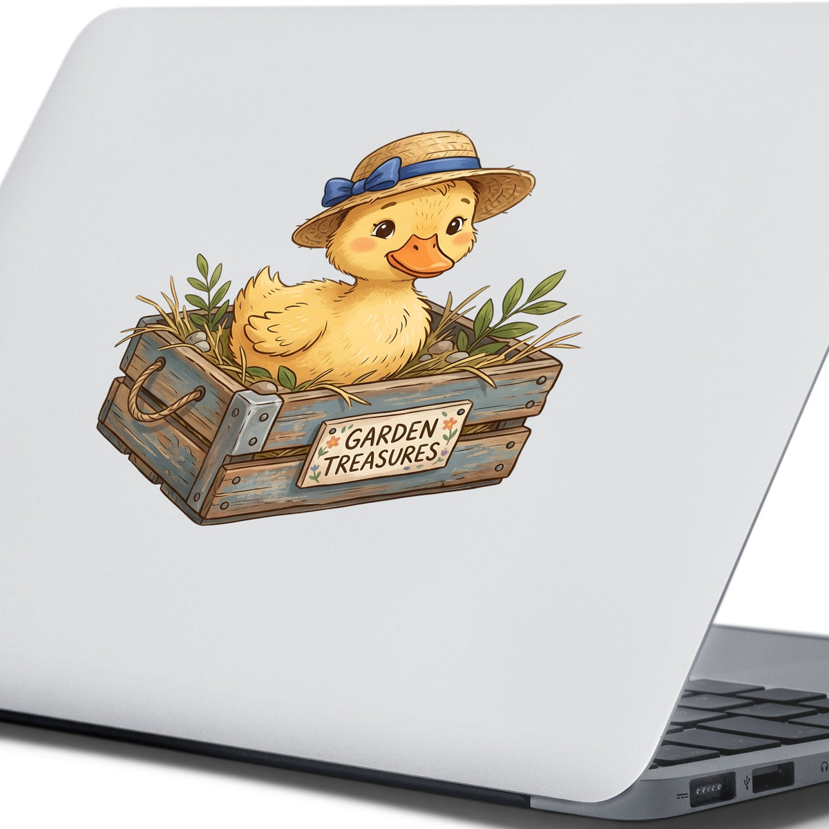 Duckling In Garden Treasures Crate UV DTF sticker applied to the lid of a silver laptop