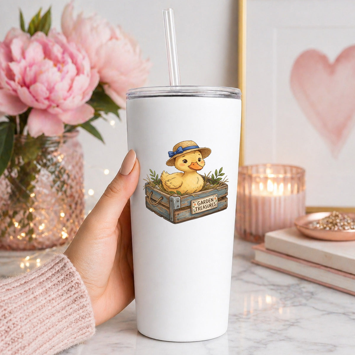 Duckling In Garden Treasures Crate UV DTF sticker applied to a white straw tumbler beside pink peonies