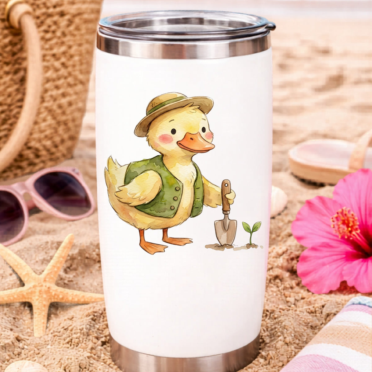 Duck In Green Vest With Garden Trowel UV DTF sticker applied to a white travel tumbler on beach sand