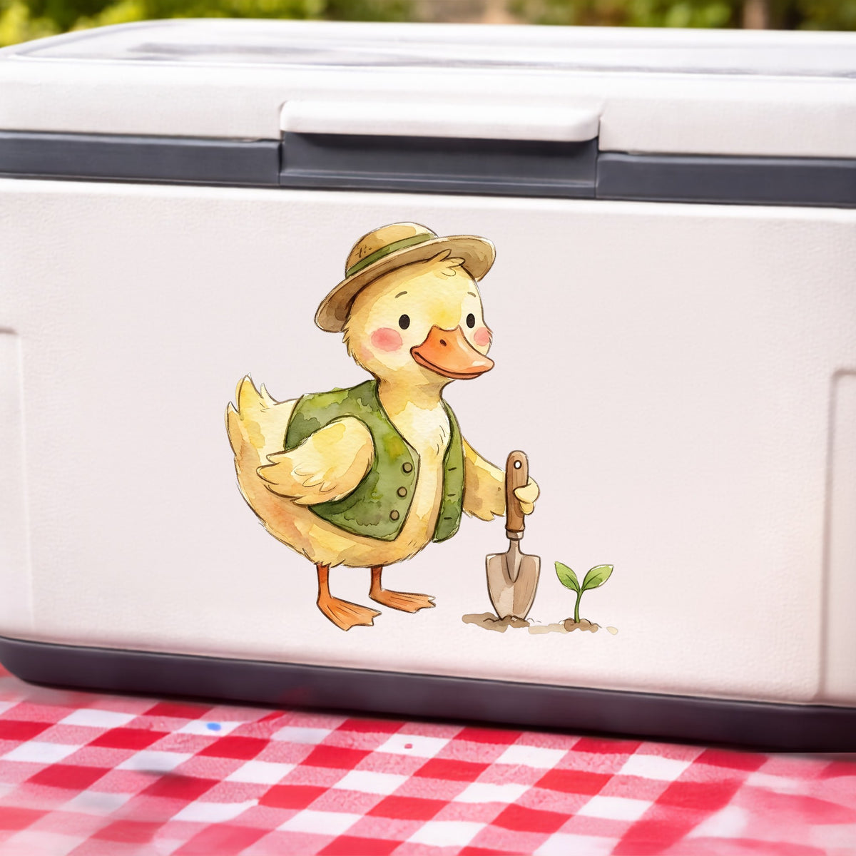 Duck In Green Vest With Garden Trowel UV DTF sticker applied to a white cooler on a red gingham cloth