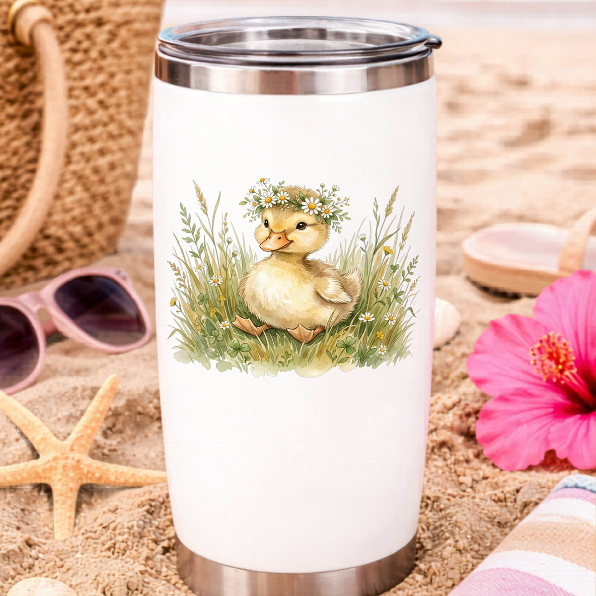 Duckling With Daisy Crown In Grass UV DTF sticker applied to a white travel tumbler on beach sand