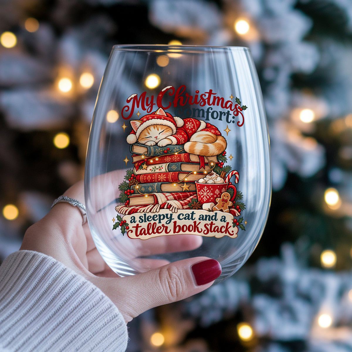 Sleepy Christmas Cat On Book Stack UV DTF sticker applied to a stemless wine glass held in hand