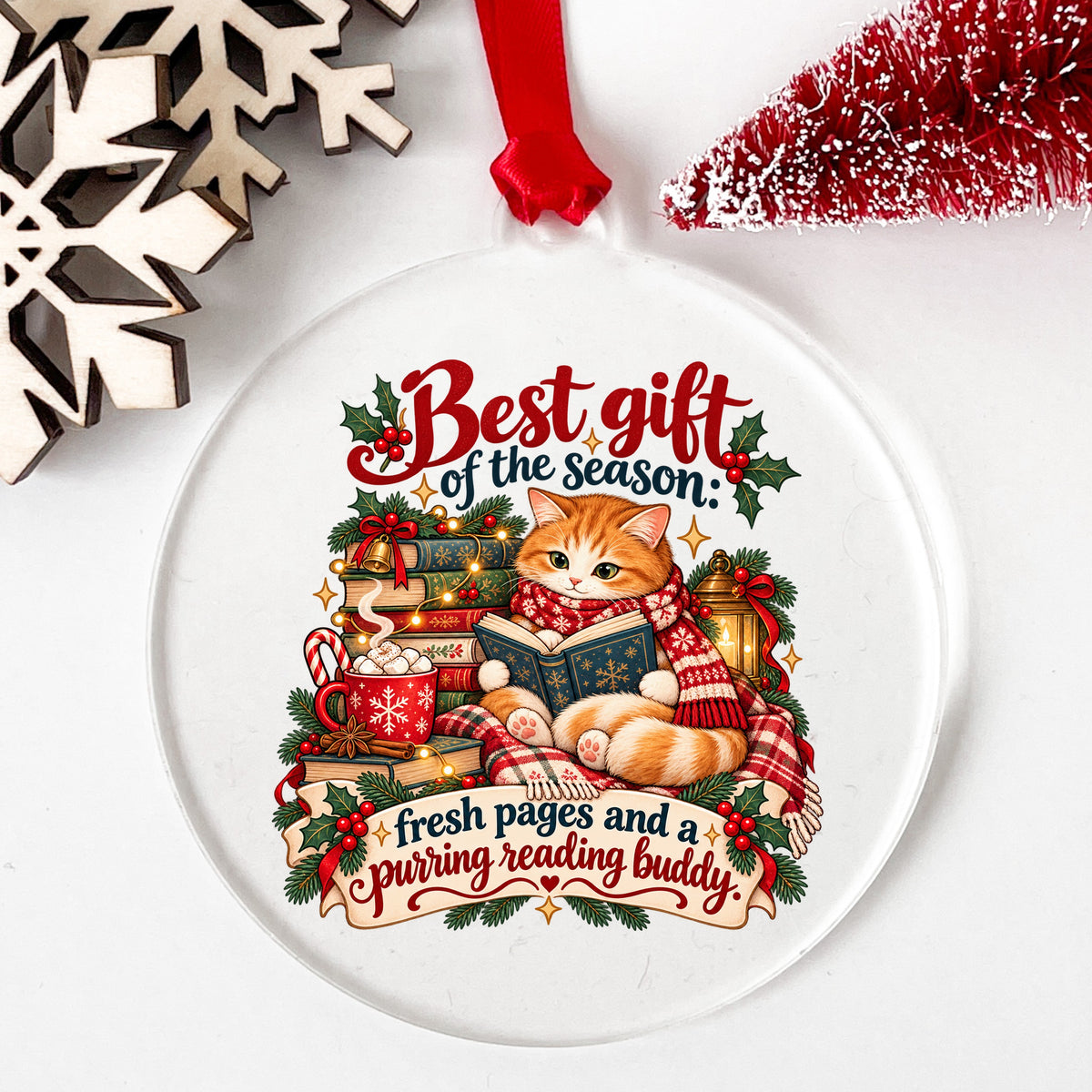 Christmas Cat Reading A Book UV DTF sticker applied to a clear round acrylic ornament with a red ribbon