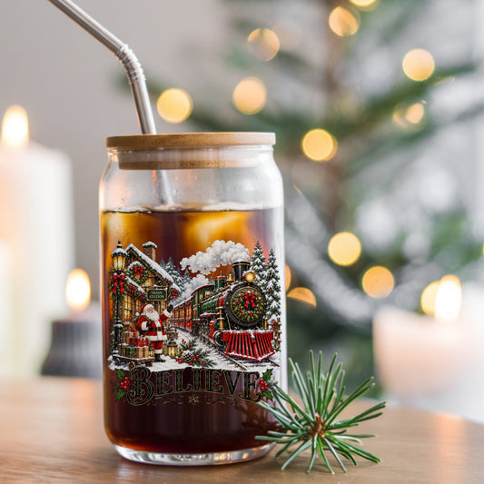 Believe Santa Christmas Train Station UV DTF sticker applied to a glass can cup of iced coffee with a straw
