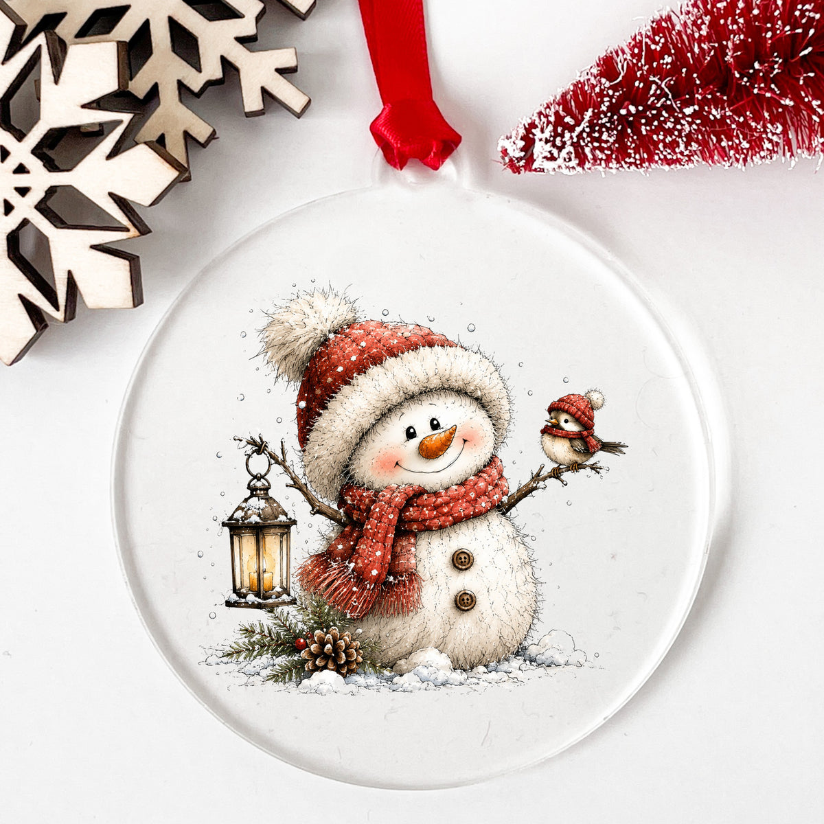 Snowman With Tiny Bird In Red Hat UV DTF sticker applied to a clear round acrylic ornament with a red ribbon