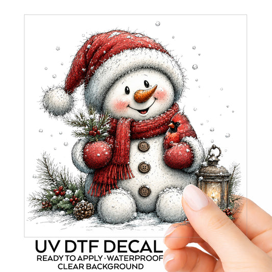 Snowman Holding Red Cardinal UV DTF sticker on its backing card, held in hand