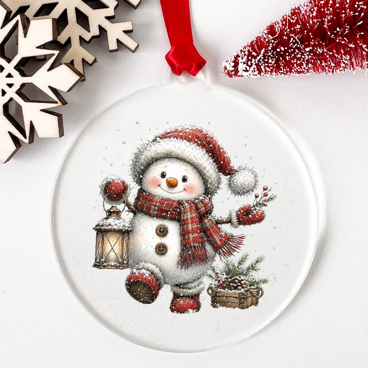 Plaid Scarf Snowman In Red Boots UV DTF sticker applied to a clear round acrylic ornament with a red ribbon
