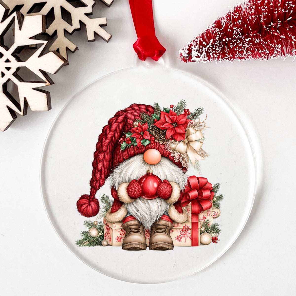 Gnome Holding Red Ornament UV DTF sticker applied to a clear round acrylic ornament with a red ribbon