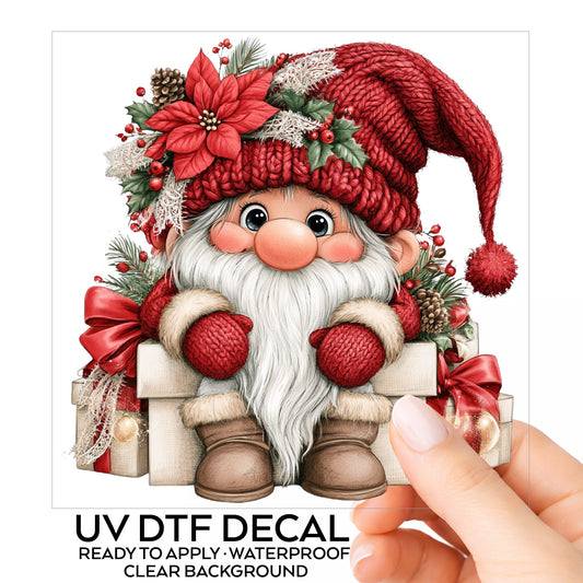 Gnome Sitting On Gift Boxes UV DTF sticker on its backing card, held in hand