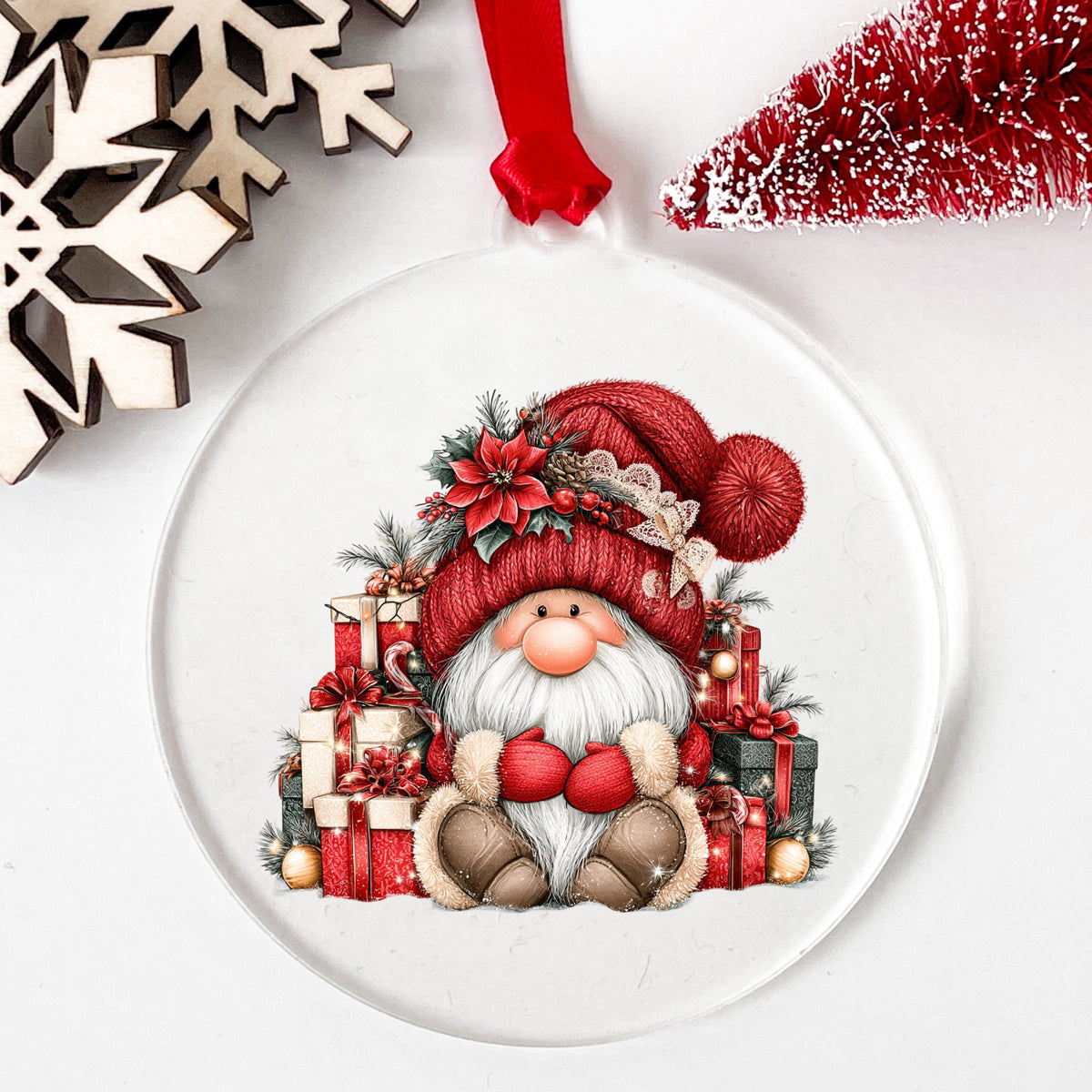 Gnome With Pile Of Presents UV DTF sticker applied to a clear round acrylic ornament with a red ribbon