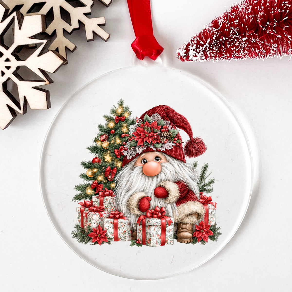 Gnome With Wrapped Presents And Lighted Tree UV DTF sticker applied to a clear round acrylic ornament with a red ribbon