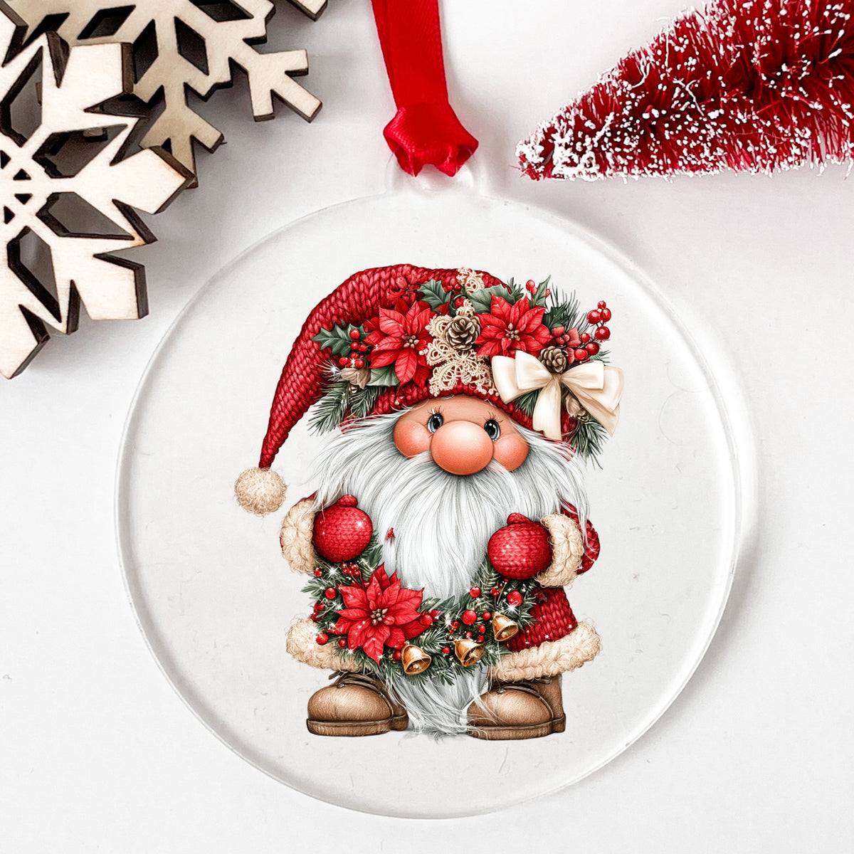 Gnome Holding Poinsettia Garland UV DTF sticker applied to a clear round acrylic ornament with a red ribbon