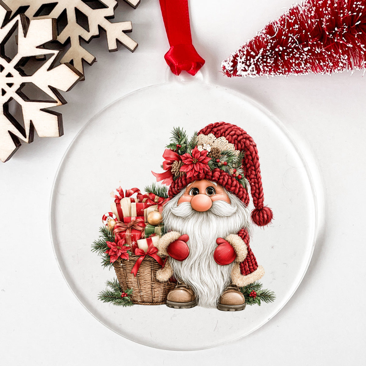 Gnome With Gift Basket UV DTF sticker applied to a clear round acrylic ornament with a red ribbon