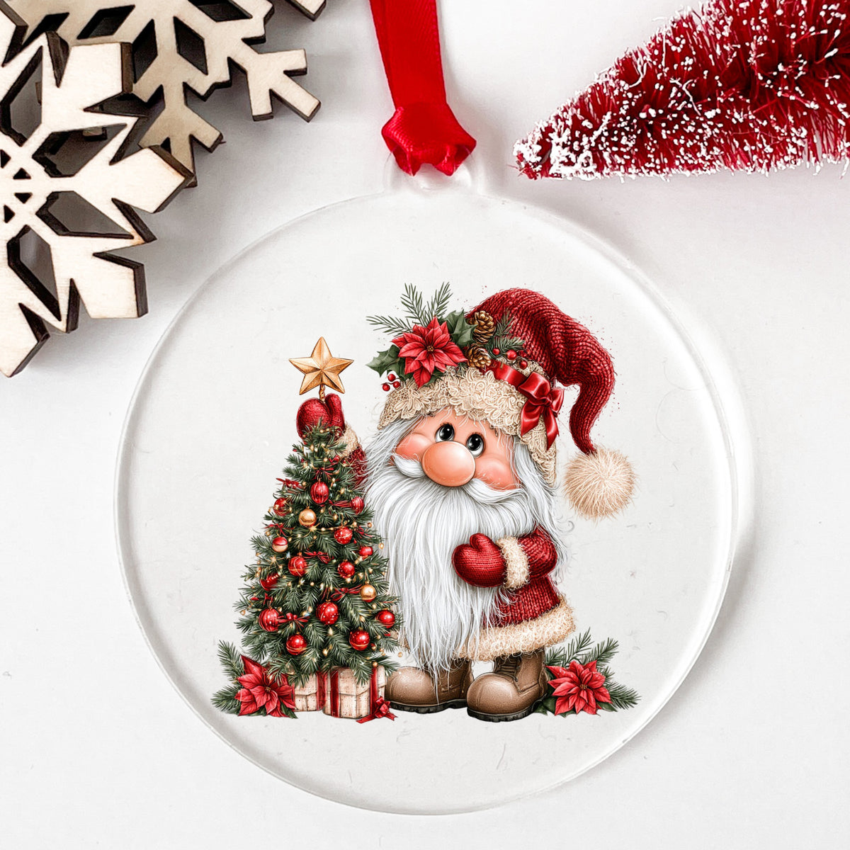 Gnome Putting Star On Christmas Tree UV DTF sticker applied to a clear round acrylic ornament with a red ribbon