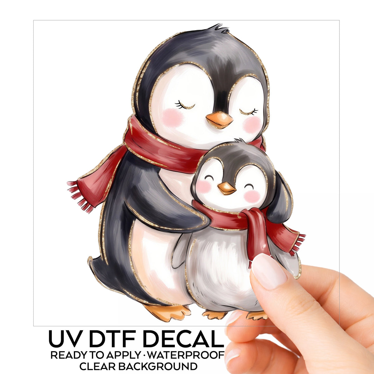 Mama And Baby Penguin In Red Scarves UV DTF sticker on its backing card, held in hand