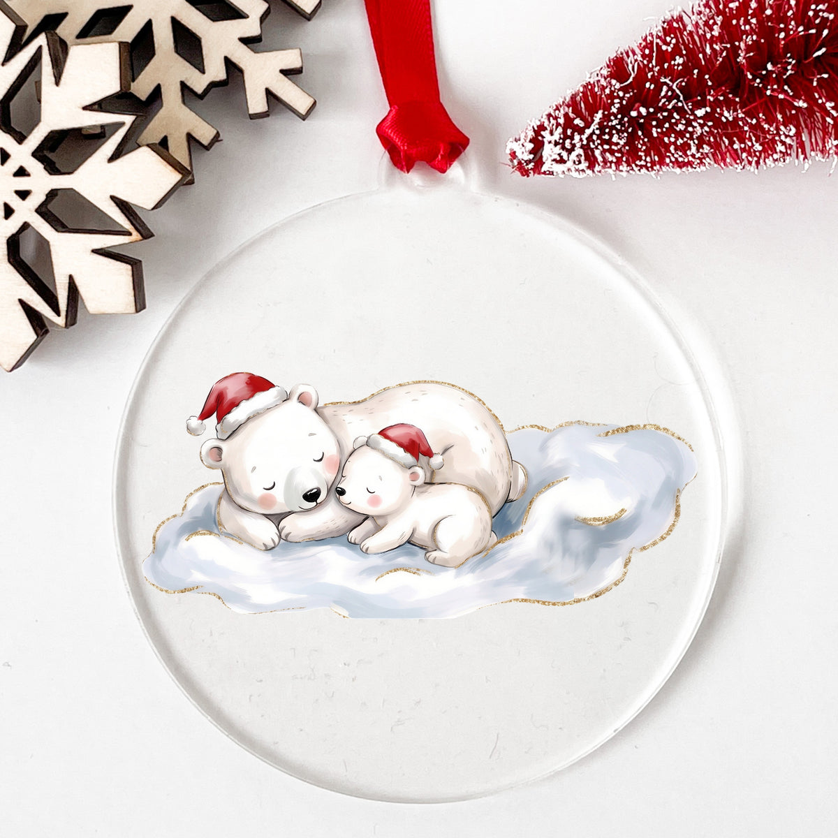 Sleeping Polar Bear And Cub In Santa Hats UV DTF sticker applied to a clear round acrylic ornament with a red ribbon