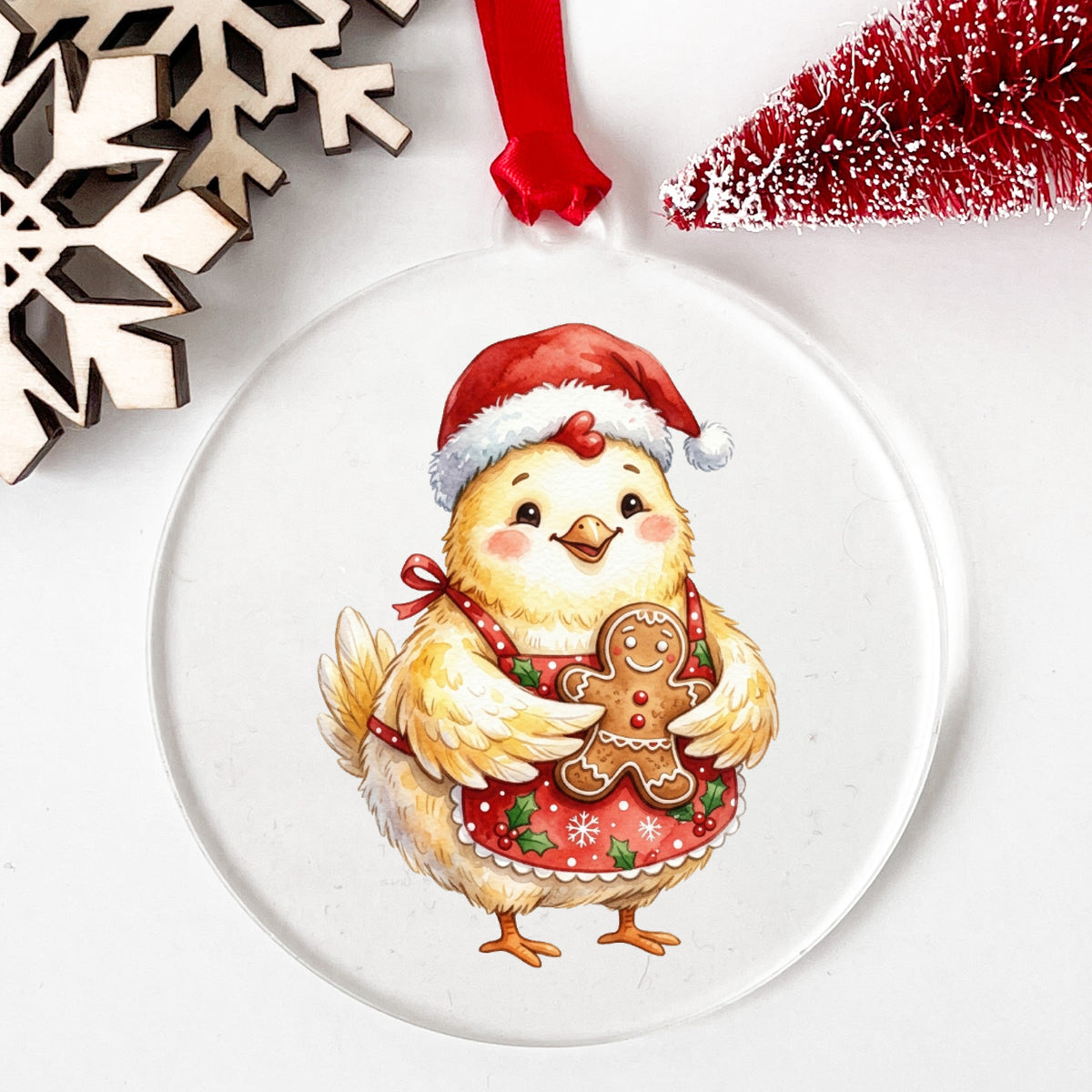 Chicken In Apron With Gingerbread Cookie UV DTF sticker applied to a clear round acrylic ornament with a red ribbon