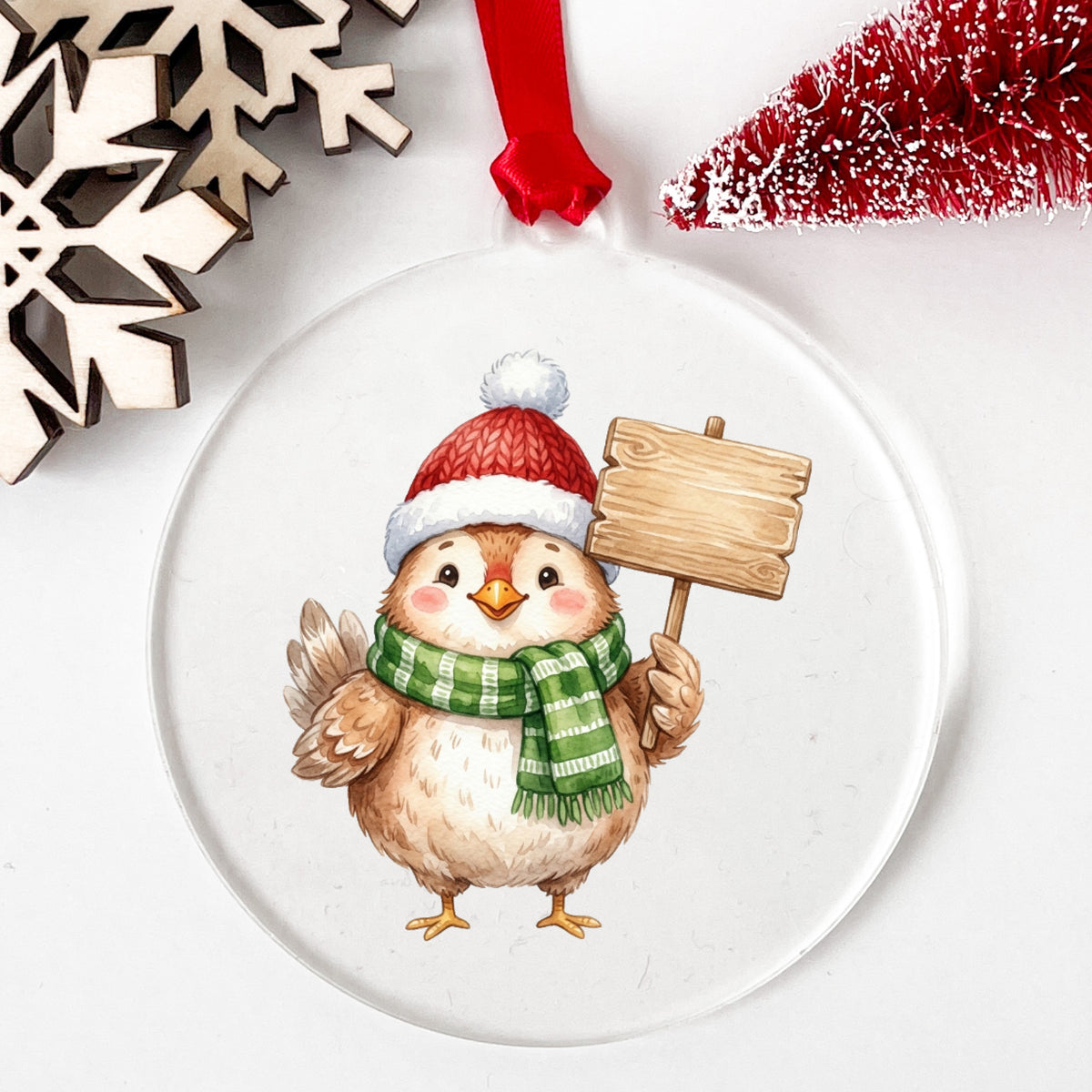 Chick With Blank Wooden Sign UV DTF sticker applied to a clear round acrylic ornament with a red ribbon