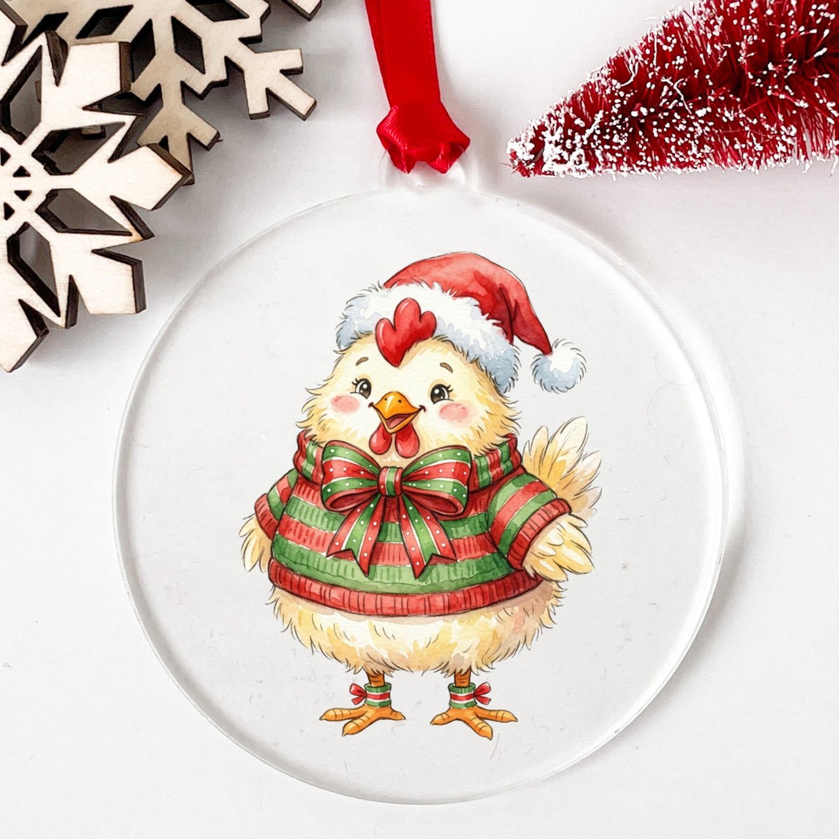 Chick In Striped Sweater With Bow UV DTF sticker applied to a clear round acrylic ornament with a red ribbon