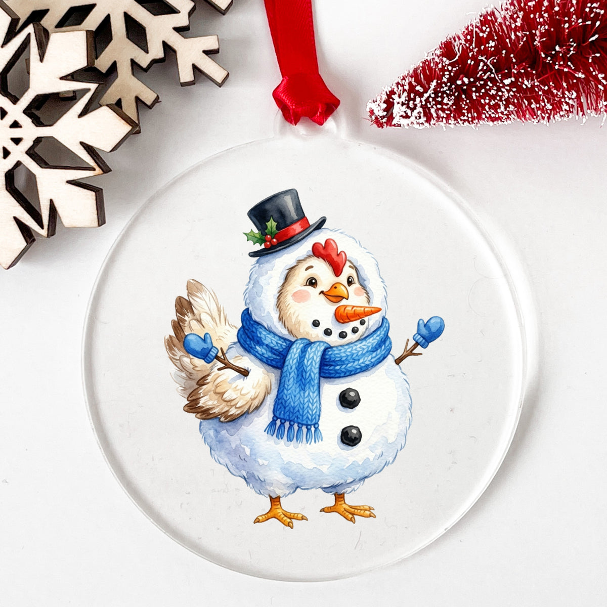 Chicken In Snowman Costume UV DTF sticker applied to a clear round acrylic ornament with a red ribbon