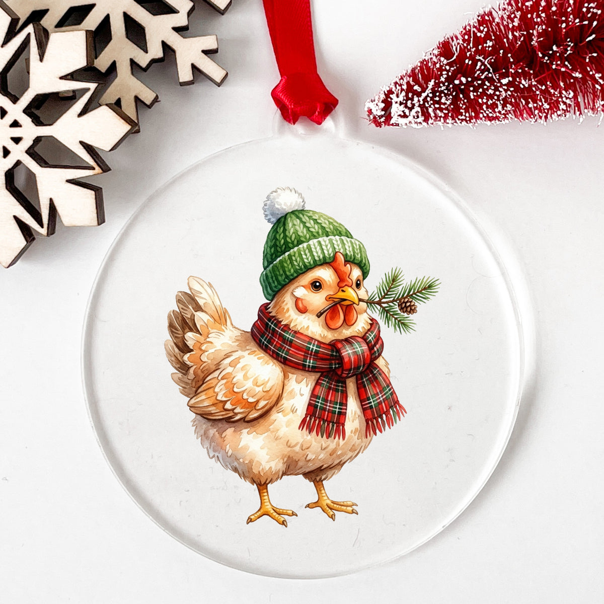 Plaid Scarf Hen With Pine Sprig UV DTF sticker applied to a clear round acrylic ornament with a red ribbon