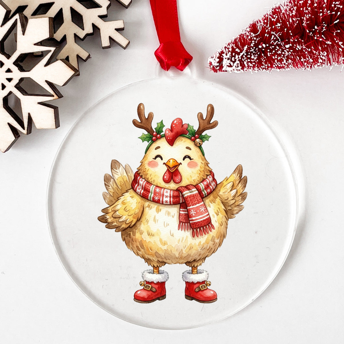 Yellow Chicken With Antlers And Red Boots UV DTF sticker applied to a clear round acrylic ornament with a red ribbon