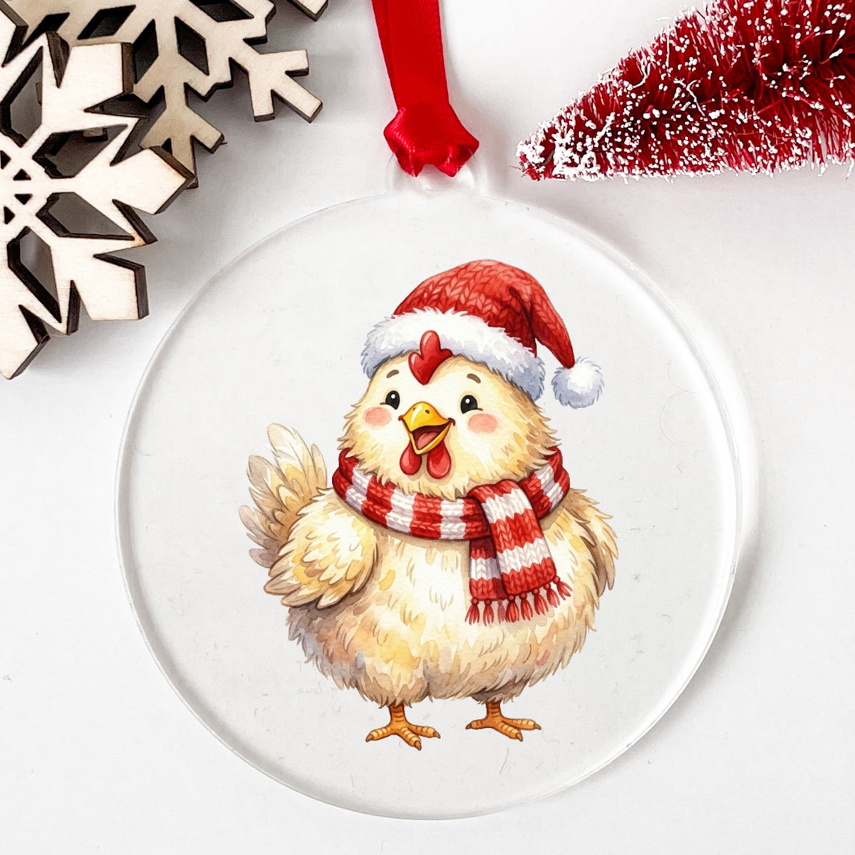 Santa Hat Chicken In Striped Scarf UV DTF sticker applied to a clear round acrylic ornament with a red ribbon