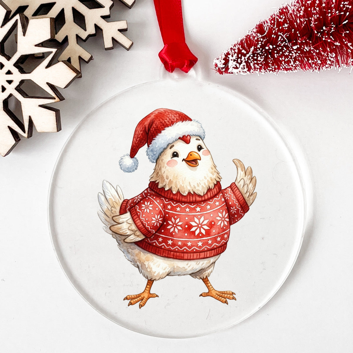 Chicken In Red Nordic Sweater UV DTF sticker applied to a clear round acrylic ornament with a red ribbon