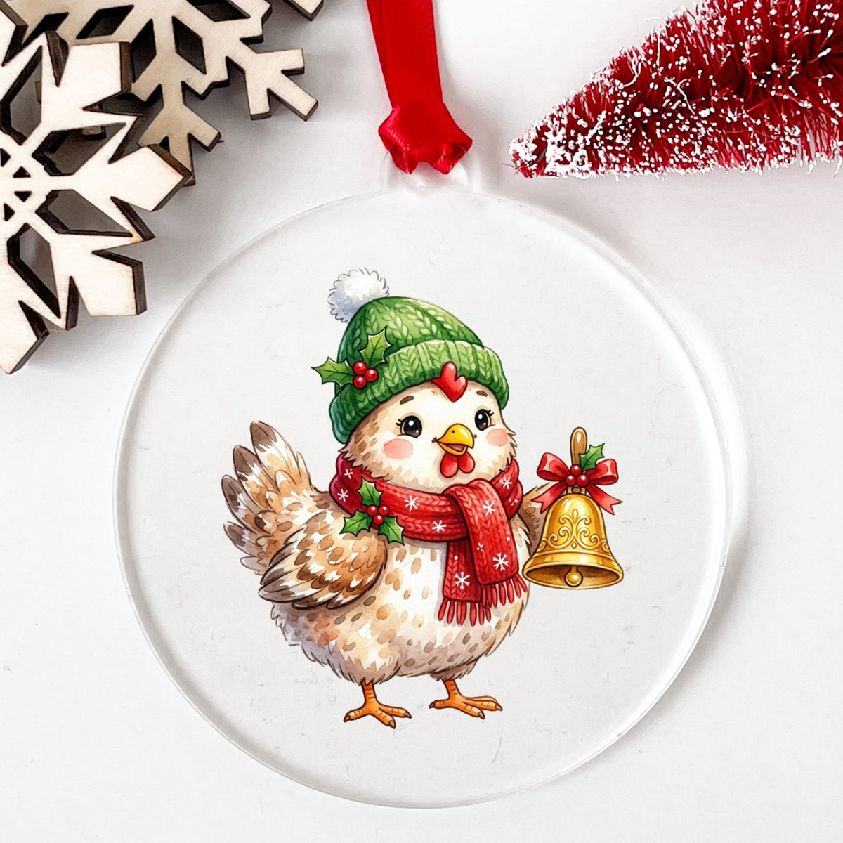 Chicken Holding Gold Jingle Bell UV DTF sticker applied to a clear round acrylic ornament with a red ribbon