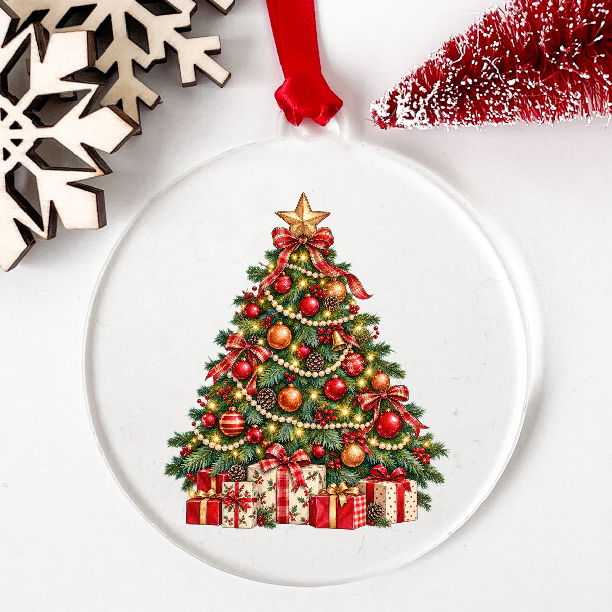 Decorated Christmas Tree With Presents UV DTF sticker applied to a clear round acrylic ornament with a red ribbon