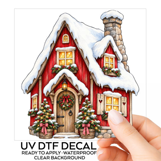 Red Christmas Cottage In Snow UV DTF sticker on its backing card, held in hand
