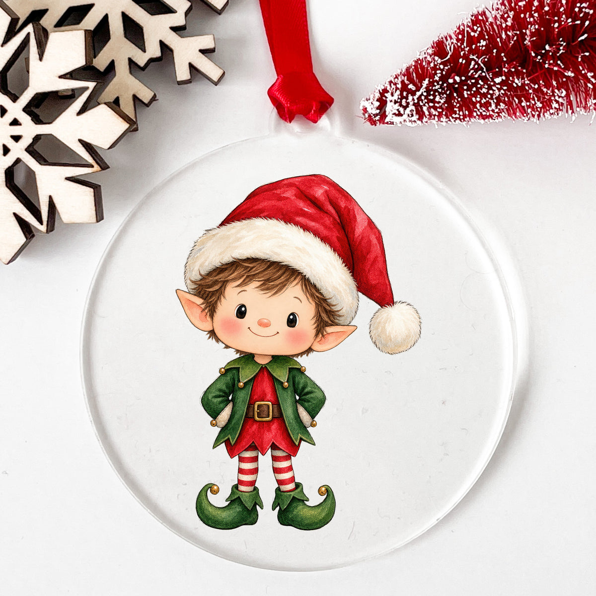Christmas Elf Boy In Santa Hat UV DTF sticker applied to a clear round acrylic ornament with a red ribbon