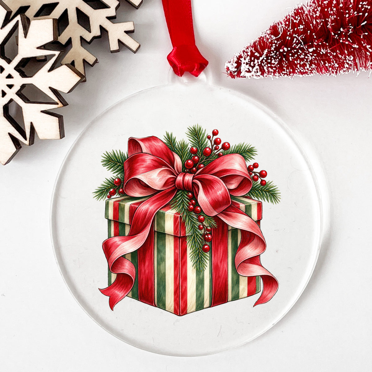 Striped Christmas Gift Box UV DTF sticker applied to a clear round acrylic ornament with a red ribbon