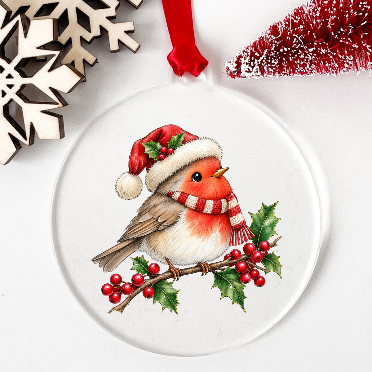 Robin In Santa Hat On Holly Branch UV DTF sticker applied to a clear round acrylic ornament with a red ribbon