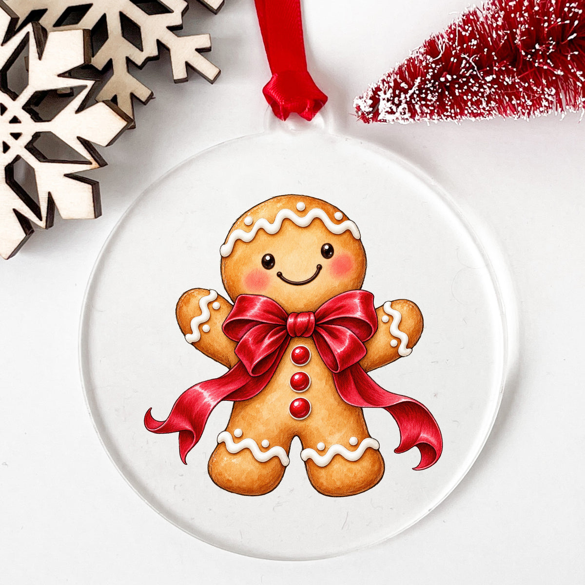 Gingerbread Man With Red Bow UV DTF sticker applied to a clear round acrylic ornament with a red ribbon
