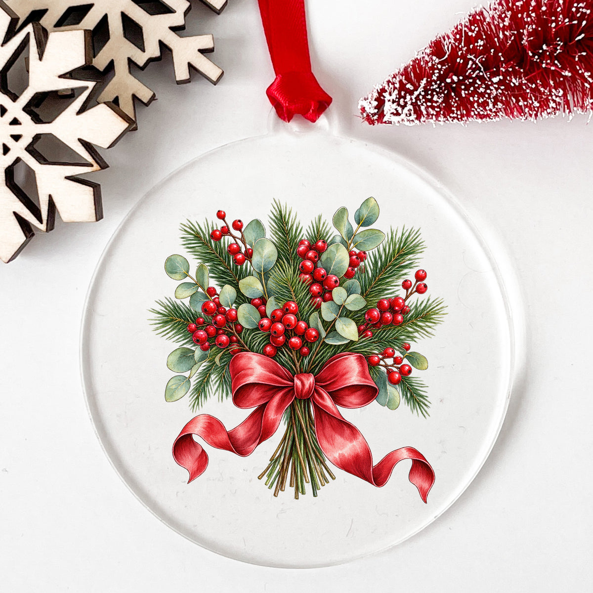 Winter Berry Bouquet With Red Bow UV DTF sticker applied to a clear round acrylic ornament with a red ribbon