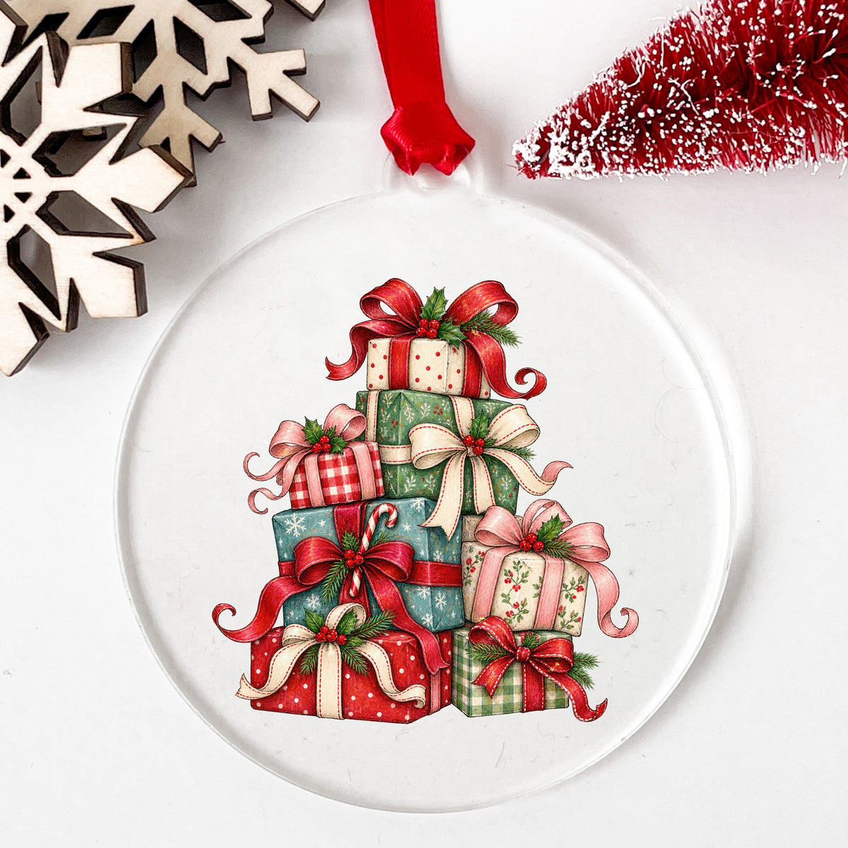 Stack Of Christmas Presents UV DTF sticker applied to a clear round acrylic ornament with a red ribbon